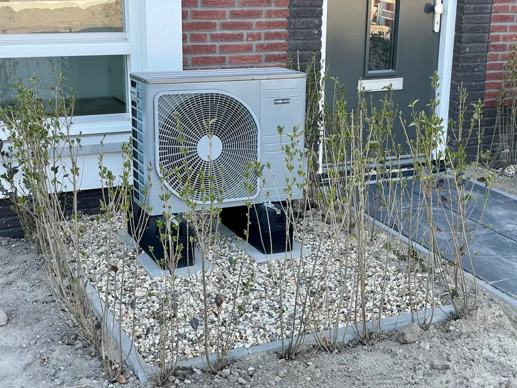 Nowoczesna pompa ciepła zainstalowana w przydomowym ogrodzie w słoneczny wiosenny dzień.
